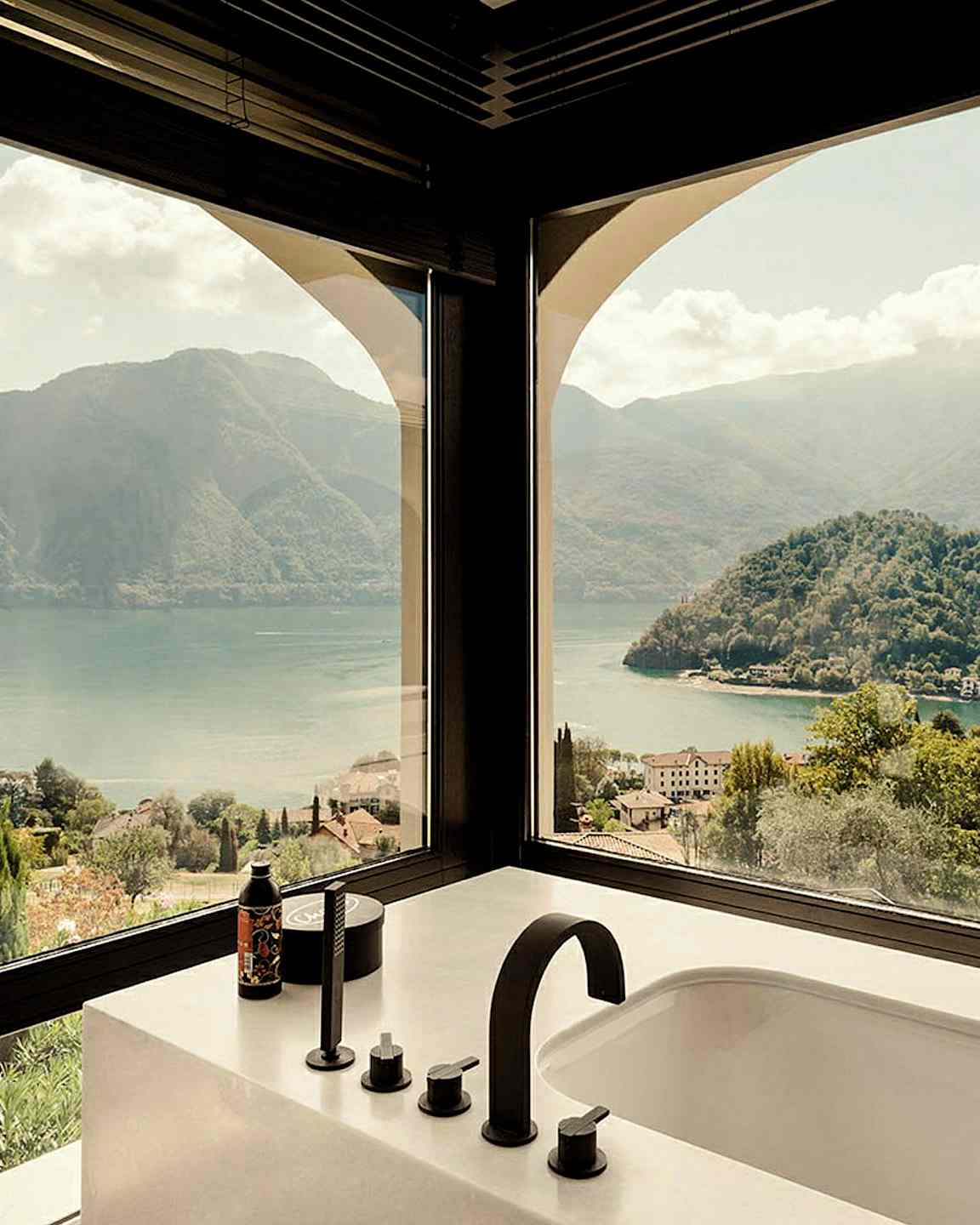 Utsikt från ett badrum med fönster mot berg och sjö. (AI-genererad text)