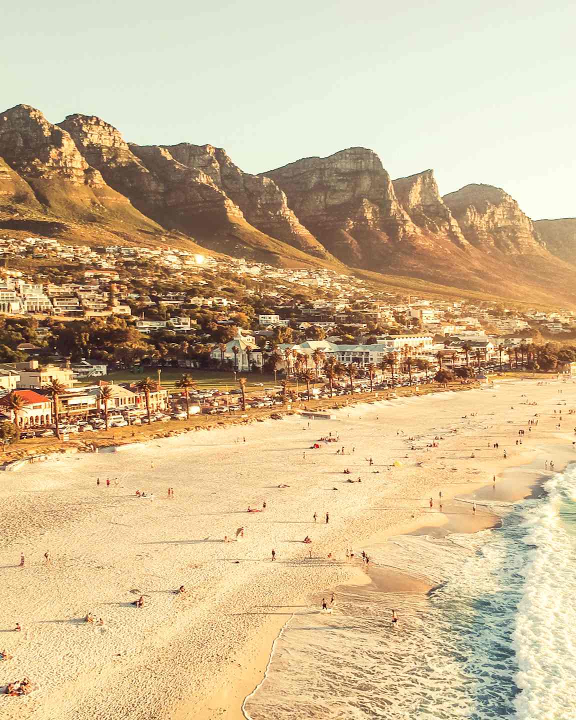 En strand framför ett bergigt område med bebyggelse. (AI-genererad text)