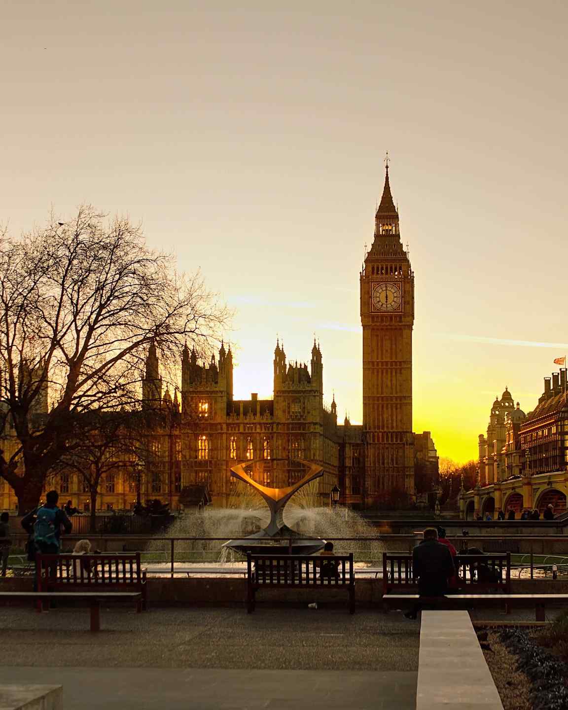 Vy över Big Ben och Westminster vid solnedgången, med en fontän i förgrunden. (AI-genererad text)