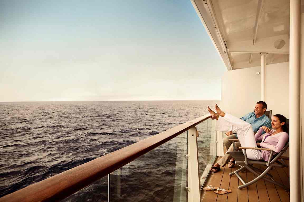 Två personer sitter avslappnat på en balkong med utsikt över havet. (AI-genererad text)