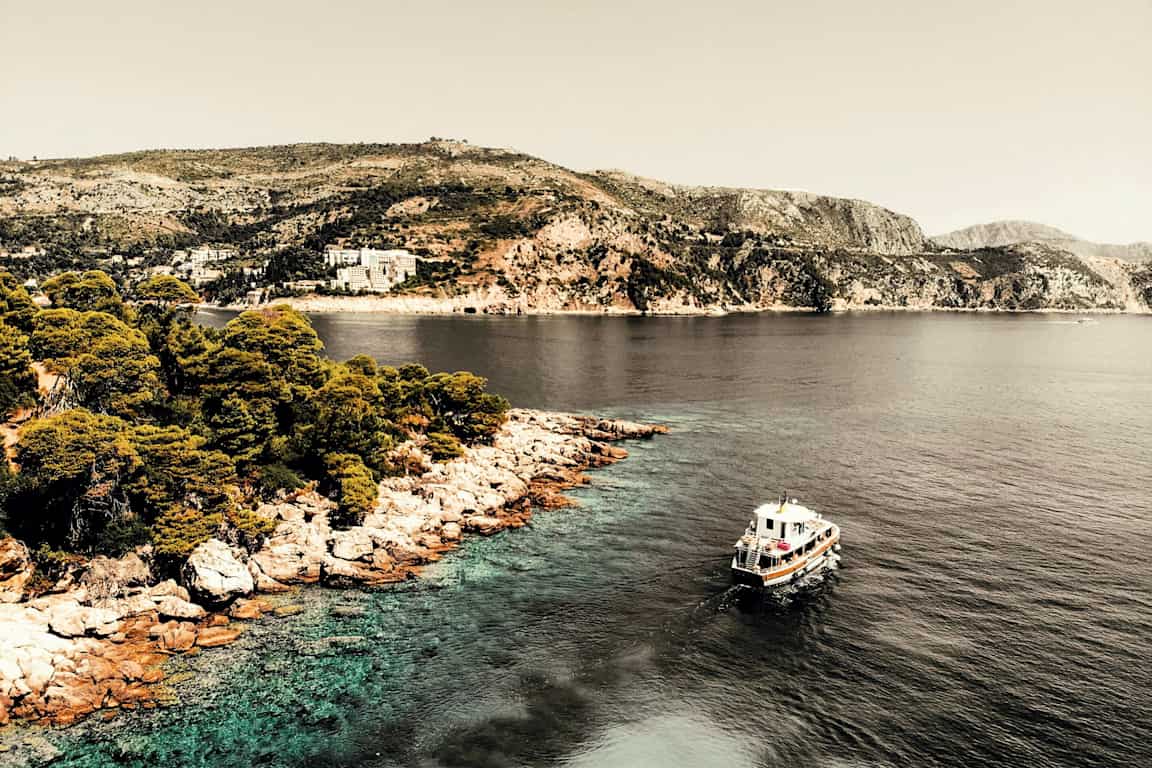 Båt på havet nära en kust med klippor och träd. (AI-genererad text)