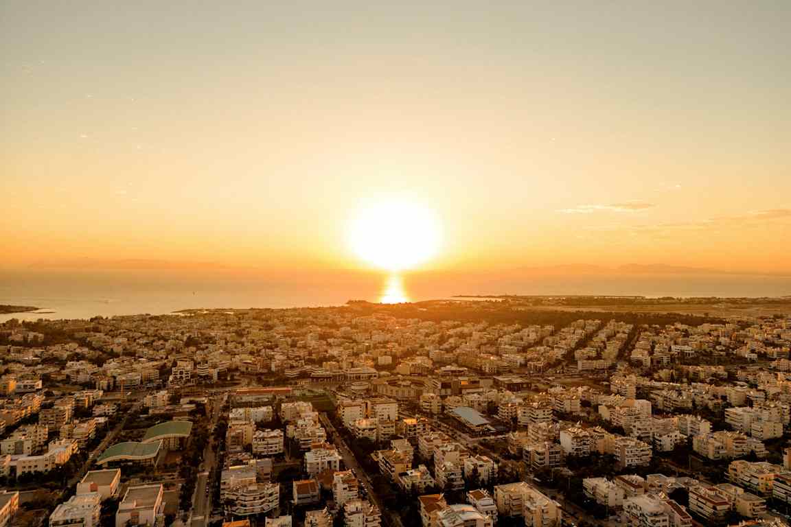 En stad fotograferad från ovan med solen som går ner vid horisonten. (AI-genererad text)