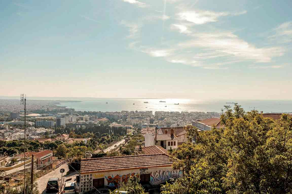 Utsikt över en stad med ett hav i bakgrunden under en klarblå himmel. (AI-genererad text)