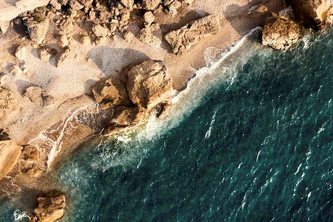 Flygvy av en stenig strand vid havet. (AI-genererad text)