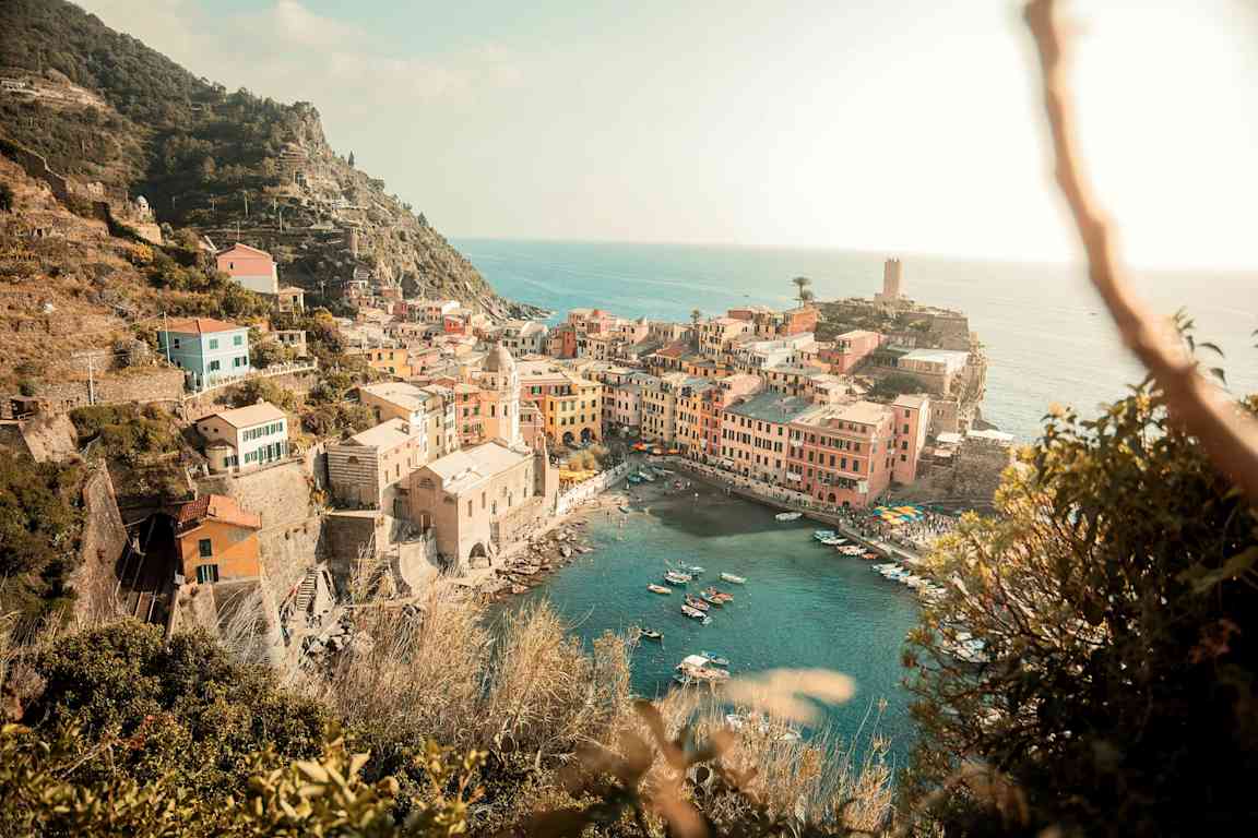 En kuststad med färgglada byggnader som vetter mot havet och små båtar i en hamn. (AI-genererad text)
