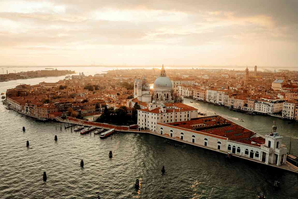 Flygvy över Venedig med kanaler, byggnader och en domkyrka vid solnedgång. (AI-genererad text)