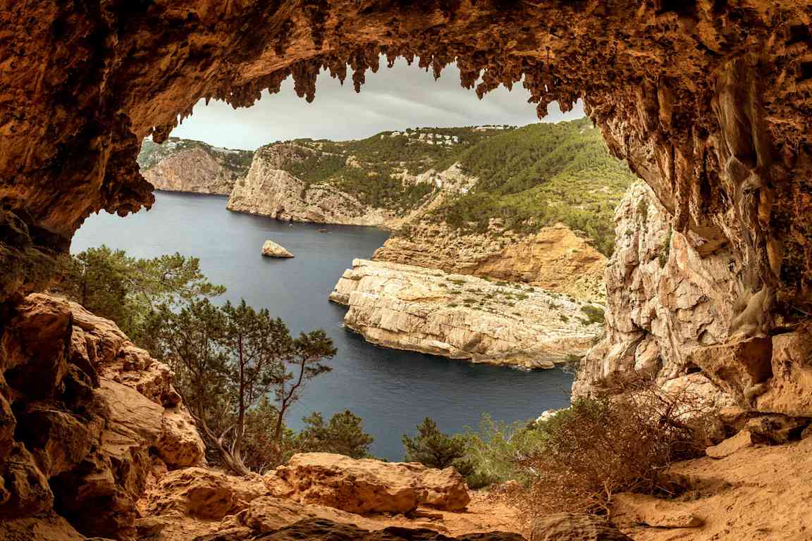 Utsikten från en grotta som vetter mot en klippig kust och hav. (AI-genererad text)