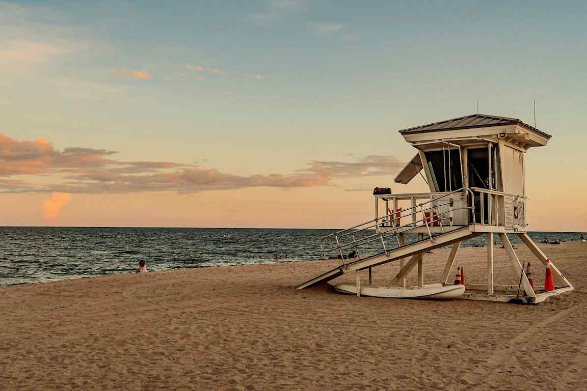 Livräddartorn på en sandstrand vid havet och solnedgången. (AI-genererad text)
