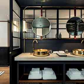 Ett modernt badrum med två runda speglar och guldtonade tvättställ. (AI-genererad text)