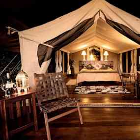 Interiören av ett lyxigt tält med säng, lampor och sittmöbler. (AI-genererad text)