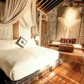 Elegant hotellrum med dubbelbädd, sittgrupp och dekorativ vägg med palmmotiv. (AI-genererad text)