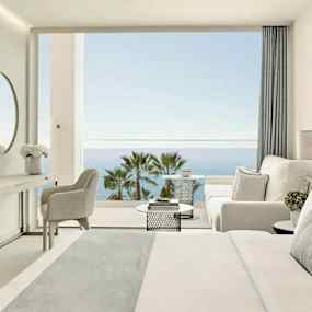 Ett hotellrum med modern inredning som har utsikt över havet och palmer. (AI-genererad text)