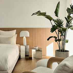 Ett sovrum med en säng, nattduksbord och en stor grön krukväxt. (AI-genererad text)
