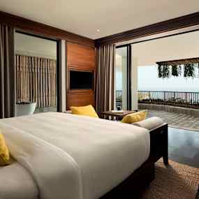 Hotellrum med en stor säng, gult dekorativt linne och en balkong med utsikt. (AI-genererad text)