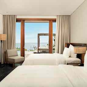 Ett hotellrum med två sängar och ett fönster som vetter mot havet. (AI-genererad text)