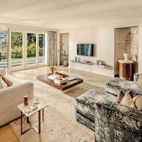 Ett vardagsrum med moderna möbler, stort fönster och utsikt över en trädgård. (AI-genererad text)