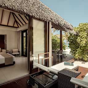 Ett hotellrum med dubbelsäng och terrass med utsikt mot grönska. (AI-genererad text)