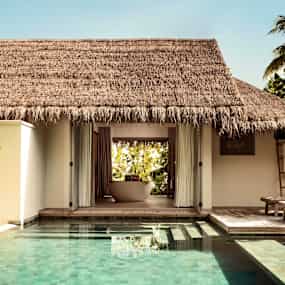 En bungalow vid sidan av en pool med terrass och solstolar. (AI-genererad text)