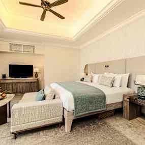 Ett hotellrum med en dubbelsäng, fåtölj, soffbord och en tv. (AI-genererad text)