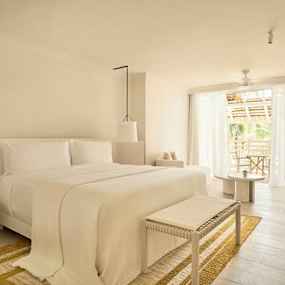 Ett ljust och stilrent sovrum med stor säng, sittmöbler och balkong med utsikt. (AI-genererad text)