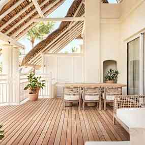 En terrass med trägolv, möbler och gröna växter. (AI-genererad text)