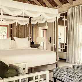 Interiör av ett rum med en himmelssäng och vardagsrumsområde. (AI-genererad text)