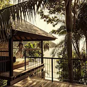 En träpaviljong med utsikt över omgivande grönska och ett vattenlandskap. (AI-genererad text)