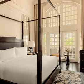 Bild av ett elegant hotellrum med en himmelsäng, stora fönster och stilfull inredning. (AI-genererad text)