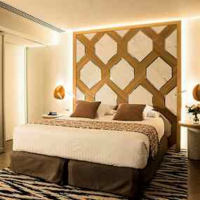 En modern dubbelsäng med dekorativ huvudgavel i ett välbelyst sovrum. (AI-genererad text)