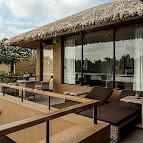 En utomhusveranda med bord och stolar, två solstolar och utsikt över vatten. (AI-genererad text)