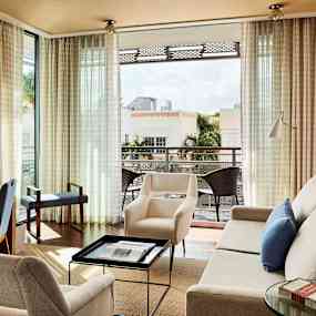 Ett ljust vardagsrum med möbler och öppen utsikt mot en balkong. (AI-genererad text)