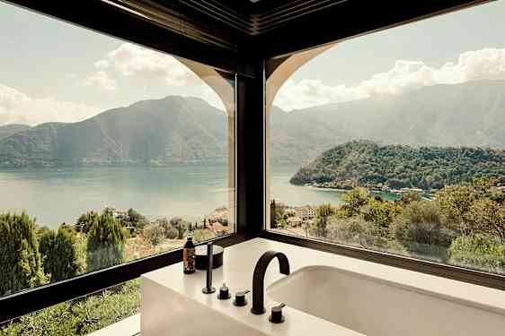 Utsikt från ett badrum med fönster mot berg och sjö. (AI-genererad text)