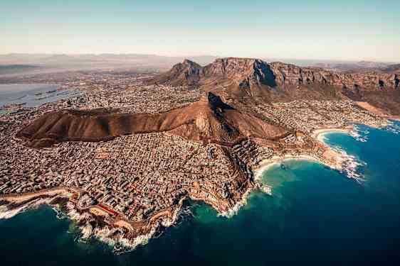 Luftbild av en stad vid foten av klippor och omgiven av havet. (AI-genererad text)