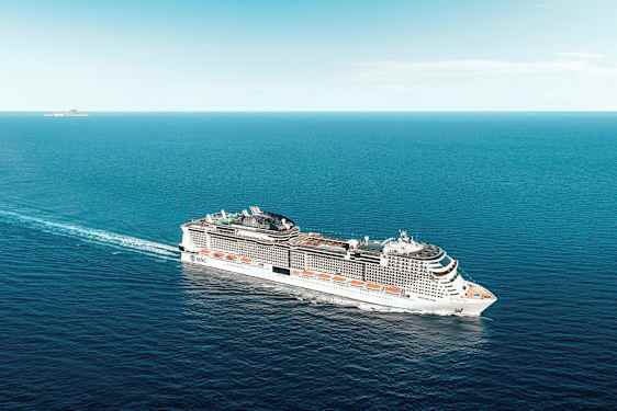 Ett stort kryssningsfartyg färdas över havet under en klar himmel. (AI-genererad text)