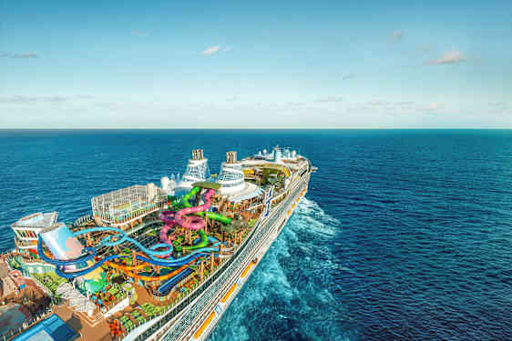 Ett stort kryssningsfartyg med vattenrutschbanor och pooler på däck, omgiven av hav (AI-genererad text)
