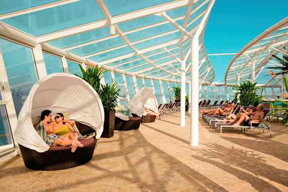 Solarium med tak från glas, solstolar och sittgrupper bredvid gröna växter. (AI-genererad text)