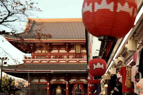 Röda lyktor hänger vid en byggnad med traditionell japansk arkitektur. (AI-genererad text)