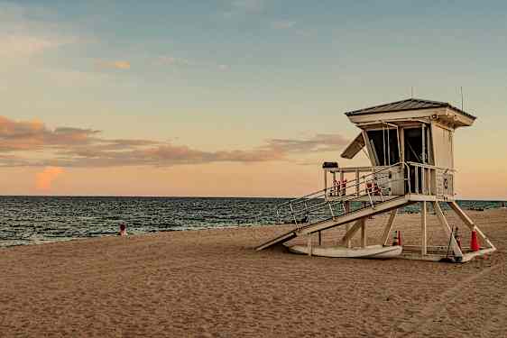 Livräddartorn på en sandstrand vid havet och solnedgången. (AI-genererad text)