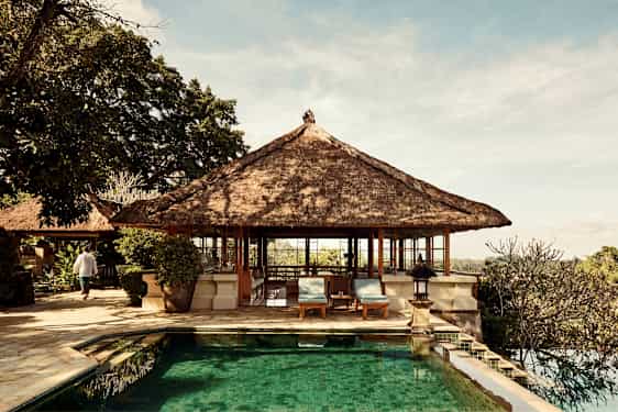 Bild på en bungalow med stråtak vid en utomhuspool. (AI-genererad text)