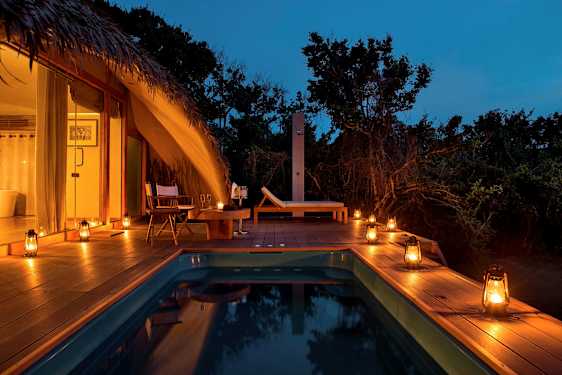 Avkopplande poolområde med tältliknande byggnad och stämningsfulla lyktor. (AI-genererad text)