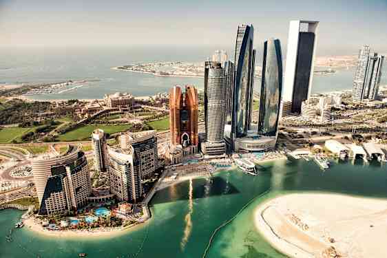 Flygfoto av Abu Dhabi med moderna skyskrapor, en sandstrand och den omgivande kusten. (AI-genererad text)