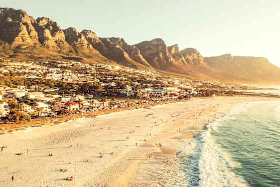 En strand framför ett bergigt område med bebyggelse. (AI-genererad text)