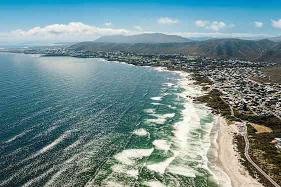 Flygfoto av en kustlinje med havet och en stad längs stranden. (AI-genererad text)