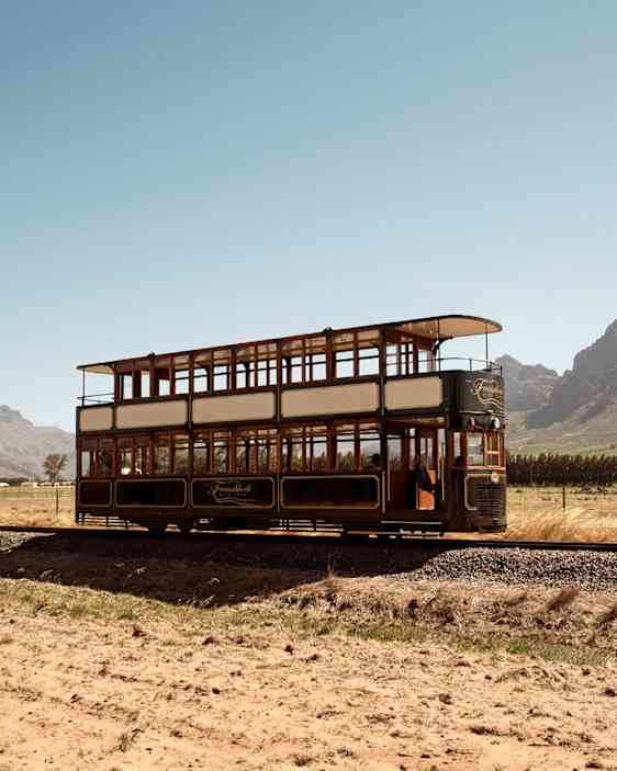 Bild av en tvåvåningsspårvagn på ett fält med berg i bakgrunden. (AI-genererad text)