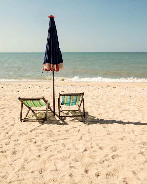 Strand med parasoll och solstolar