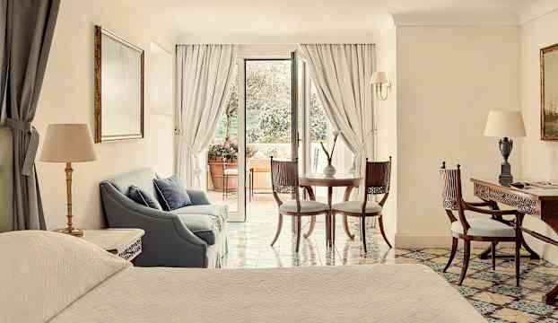 Ett elegant hotellrum med sittgrupp och utsikt mot en terrass. (AI-genererad text)