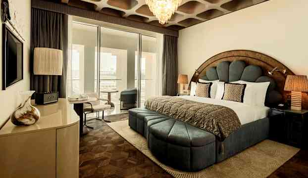 Bild av ett elegant hotellrum med säng, dekorativa möbler och stora fönster. (AI-genererad text)