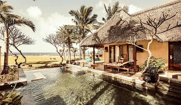 Villa med pool, palmer och hav i bakgrunden. (AI-genererad text)