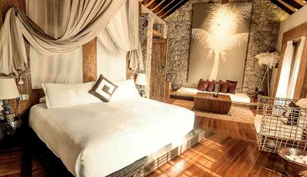 Elegant hotellrum med dubbelbädd, sittgrupp och dekorativ vägg med palmmotiv. (AI-genererad text)