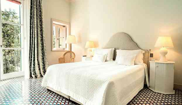 Sovrum med dubbelsäng, vita sängkläder och sidobord med lampor. (AI-genererad text)